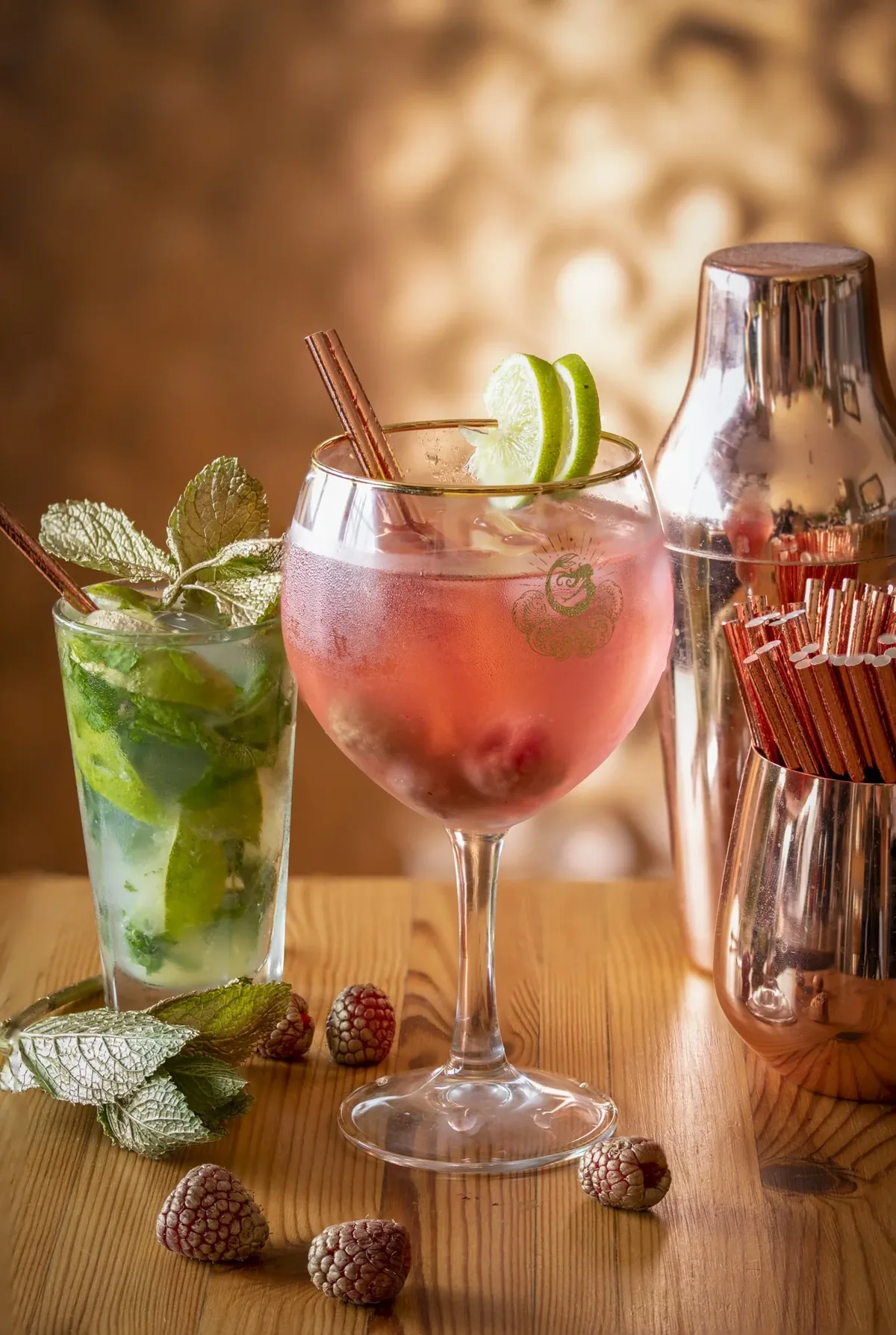 Two cocktails and a copper shaker on the bar