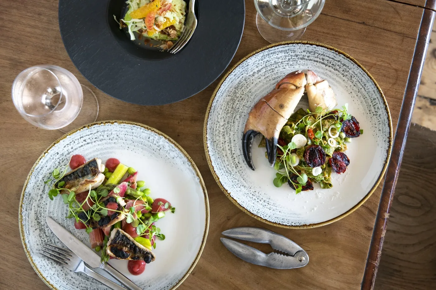 Two plated seafood dishes photographed from above on a wooden table