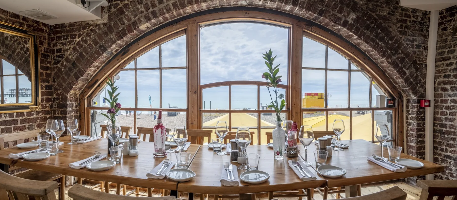 The dining room inside the brick arches, laid tables facing tall arched windows onto Brighton seafront