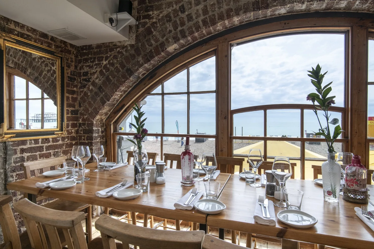A laid table for two beside one of the restaurant's tall arched windows looking out to sea